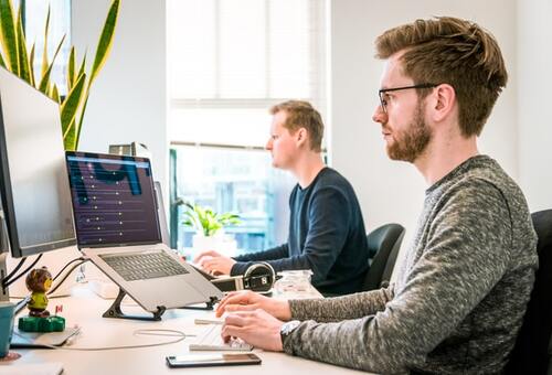 Deux hommes en train de travailler sur leur ordinateur.